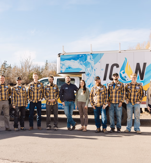 The ICON Plumbing team stands together in front of a branded white work truck under a bright blue sky.